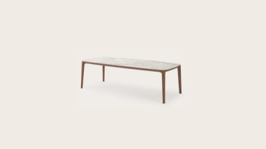 Rechthoekige eettafel met afgeronde hoeken, licht steenlook blad en slanke houten poten.