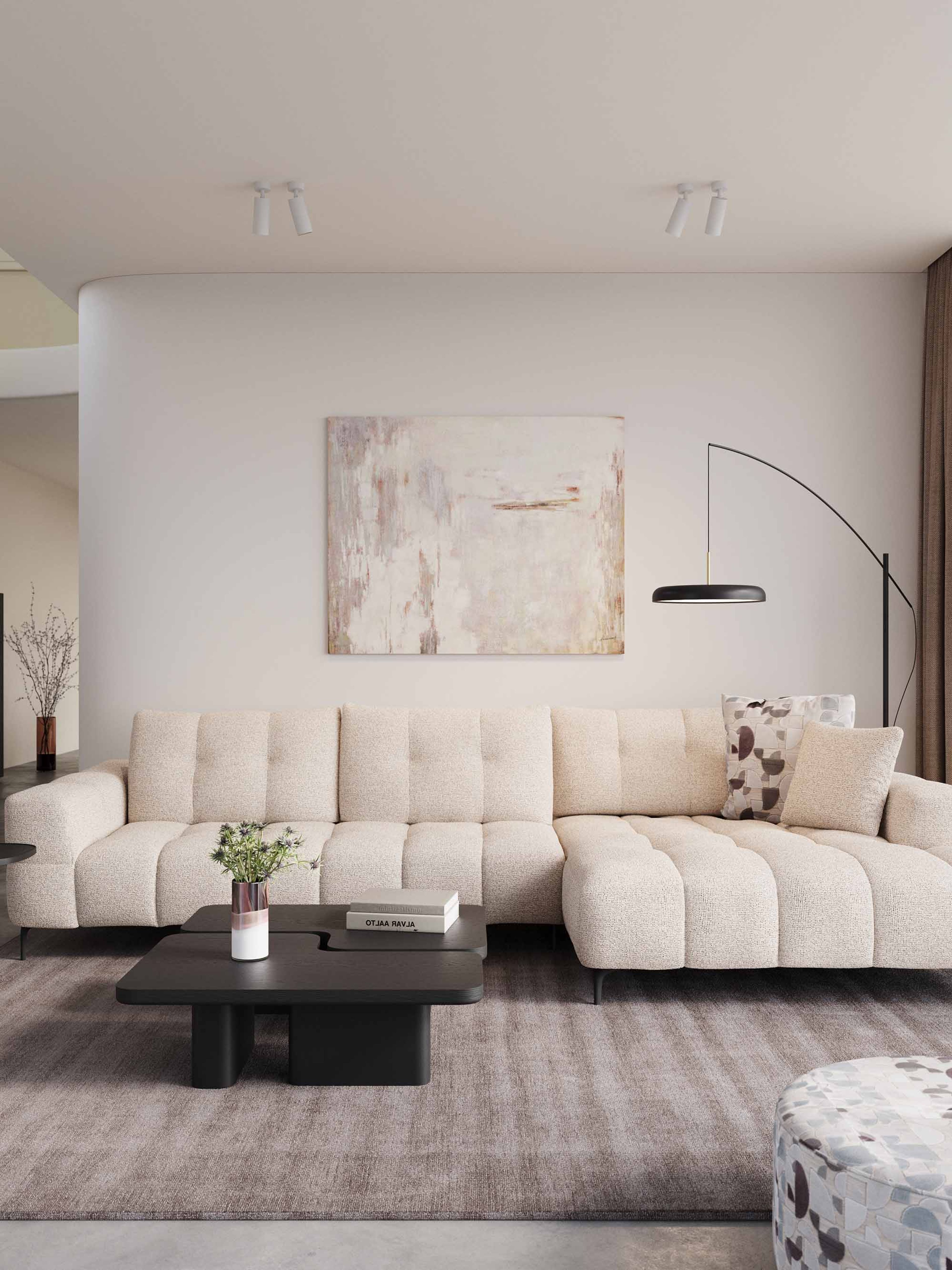 Beige hoekzetel Isola in lichte woonkamer met grote ramen, houten boekenkast, lage salontafel en zachte natuurlijke materialen.