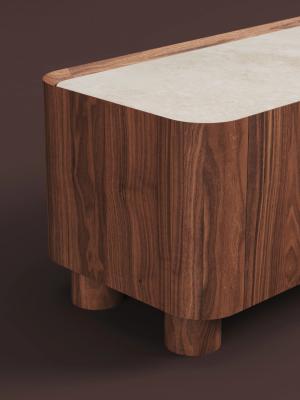 Detailbeeld van een houten kast met warme houtnerf, afgeronde hoeken en een lichtgekleurd bovenblad.