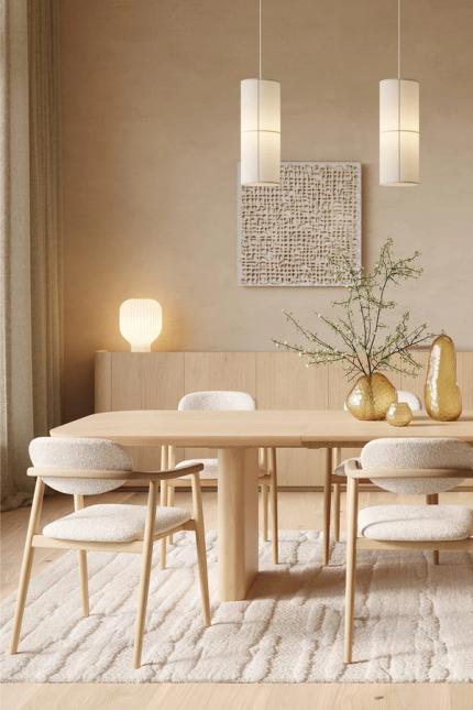 Japandi eetkamer met lange houten tafel en lichte stoelen op een zacht tapijt, met rustige decoratie en zicht op de zithoek.