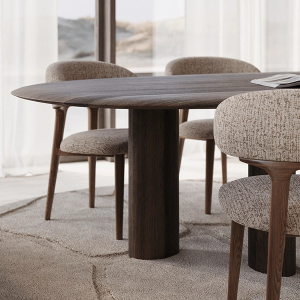 Detailbeeld van een lichte eettafel met een zacht afgerond, organisch gevormd tafelblad en subtiele steenstructuur, omringd door licht gestoffeerde stoelen met houten poten.