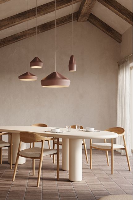 Salle à manger lumineuse avec table ovale et chaises en bois, suspensions aux tons chauds, grandes fenêtres sur l’extérieur et buffet minimaliste.