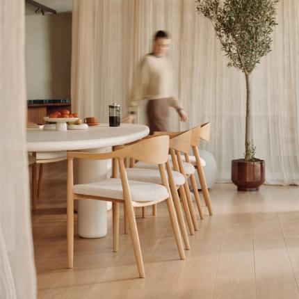Table Artisano dans une salle à manger lumineuse avec chaises en bois et assises tissu; fruits et café sur la table.