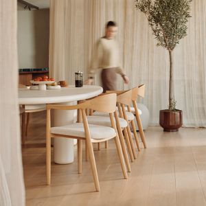 Table Artisano dans une salle à manger lumineuse avec chaises en bois et assises tissu; fruits et café sur la table.