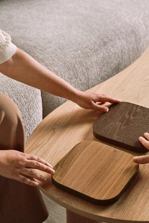 Handen plaatsen een licht stenen staaltje op een houten oppervlak