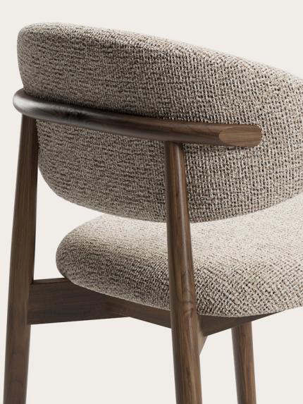 Detail van Piola eetkamerstoel met gestoffeerde rug en zitting in beige stof en walnootkleurig houten frame.