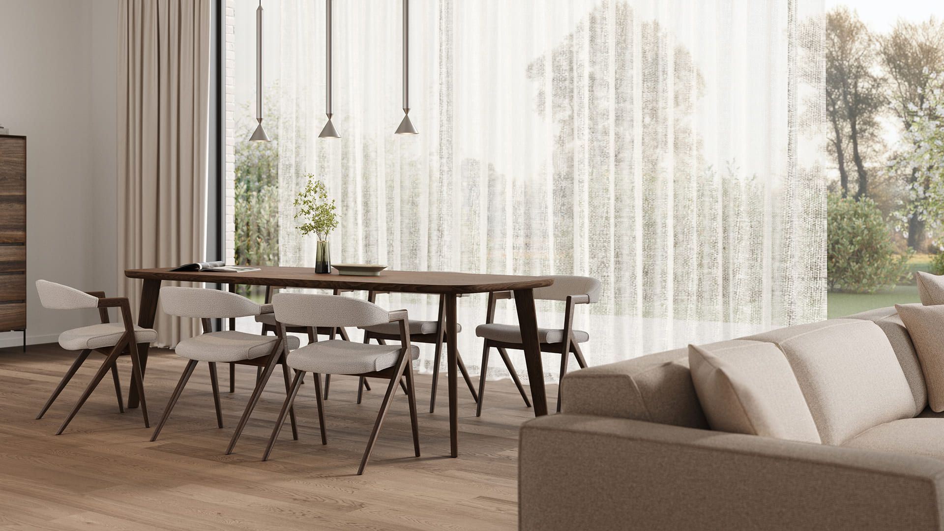 Lichte woonkamer met houten eettafel en gestoffeerde stoelen bij grote ramen met transparante gordijnen; een beige zetel op de voorgrond.