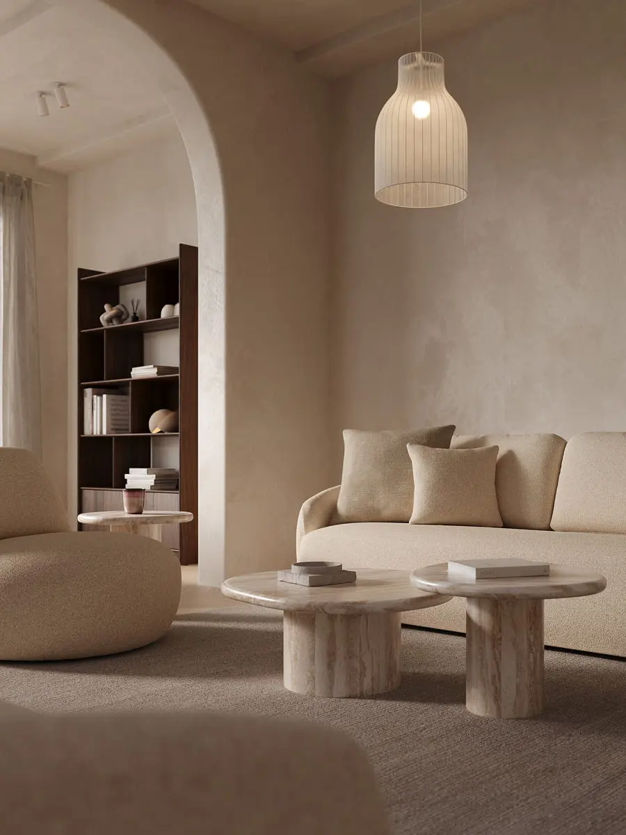 "Canapé Tomar en tissu beige doux avec des formes arrondies, tables basses en marbre, lampe suspendue et grande bibliothèque en bois dans la niche.