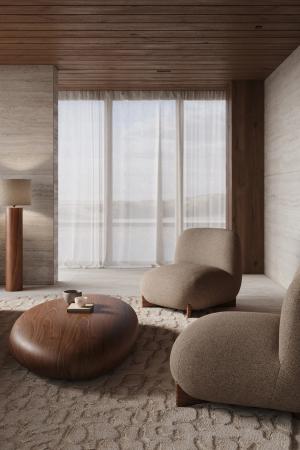 Beige fauteuils met afgeronde vormen rond een organische houten salontafel in een warme woonkamer met grote ramen.