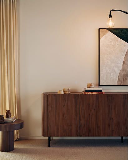 Donker houten dressoir met afgeronde hoeken en licht bovenblad, gecombineerd met kunst en decoratieve objecten.