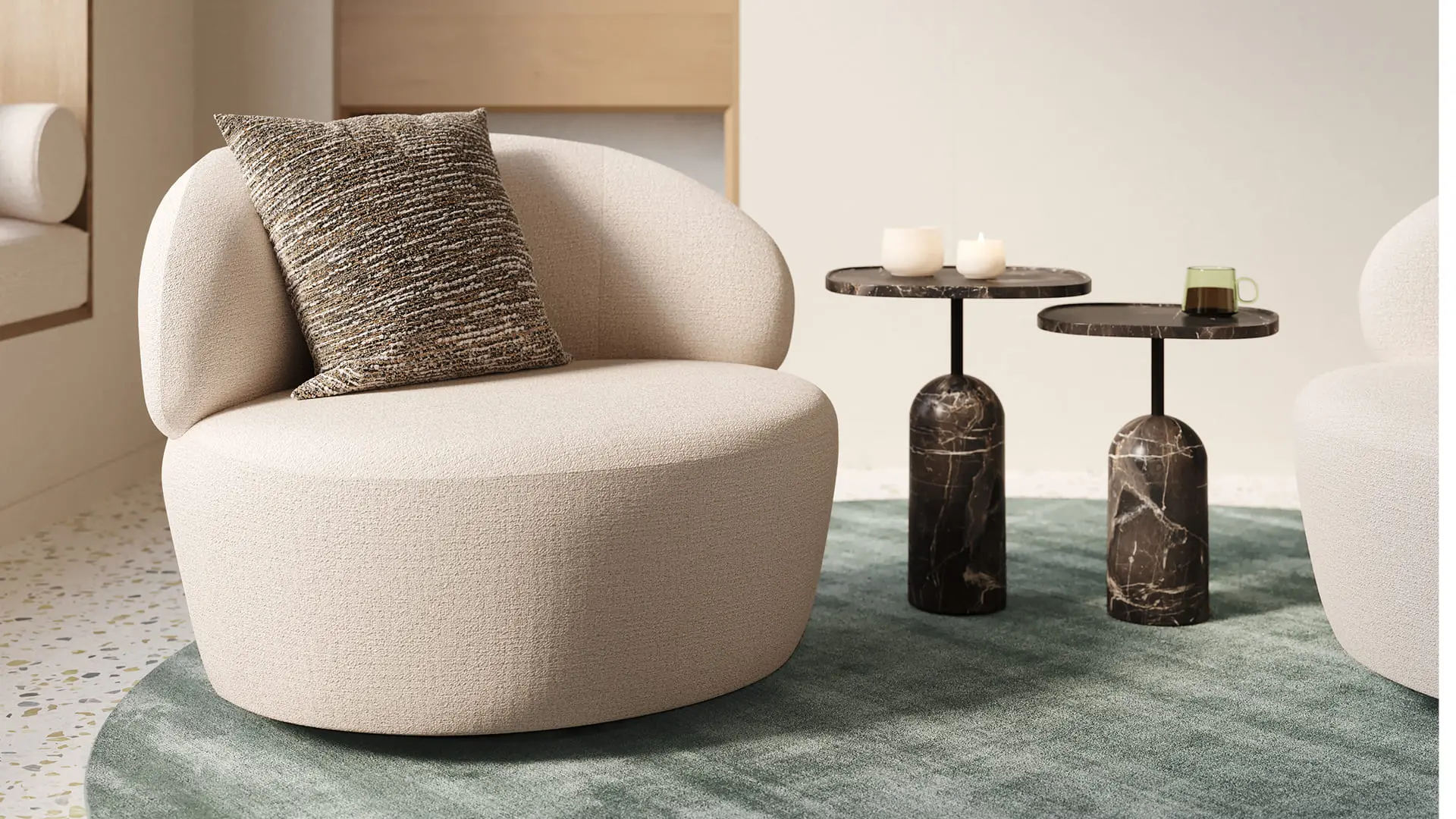 Norcia fauteuil met ronde, organische vorm in crèmekleurige stof, afgewerkt met een decoratief sierkussen in gemêleerde bruintinten.