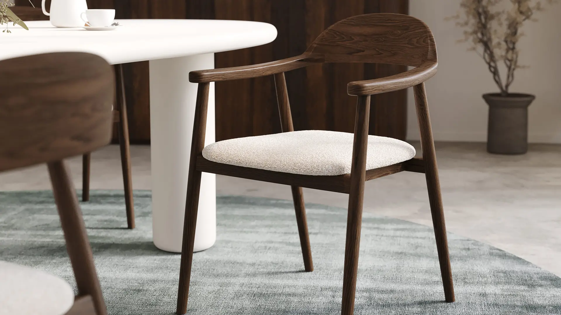 Chaise Comino en bois foncé avec assise beige clair près d’une table ronde blanche, sur tapis vert bleuté.