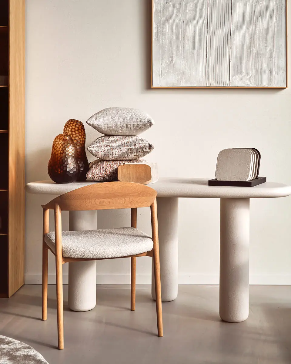 Table à manger avec une chaise en bois, des coussins empilés et des objets décoratifs.