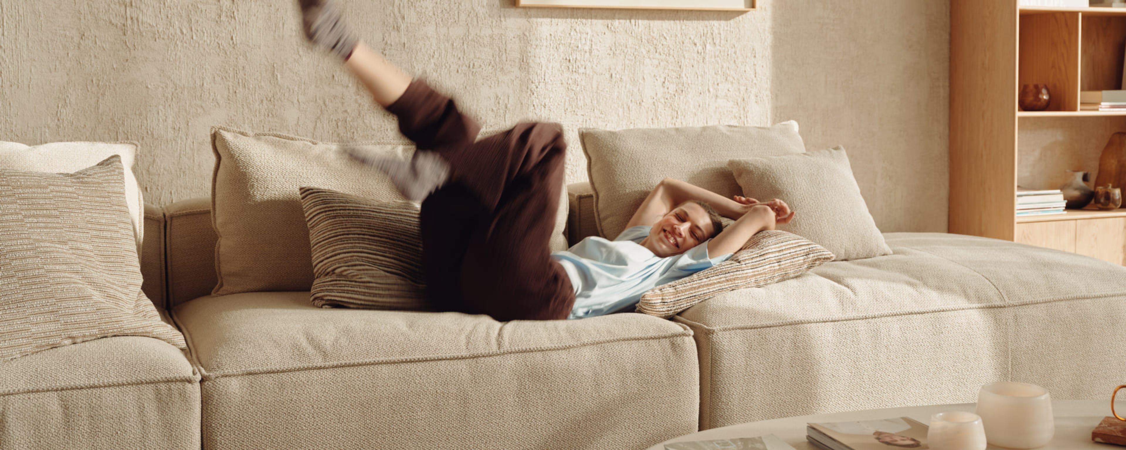 Vrouw speelt uitgelaten op een comfortabele zetel in een warm huiselijk interieur