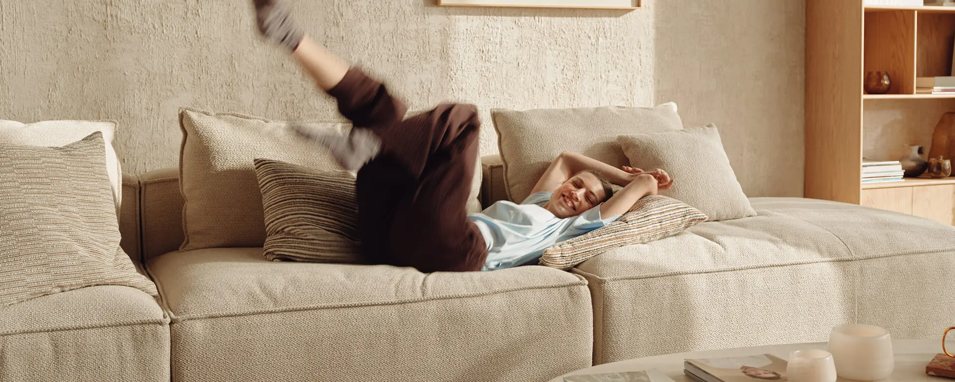 Vrouw speelt uitgelaten op een comfortabele zetel in een warm huiselijk interieur