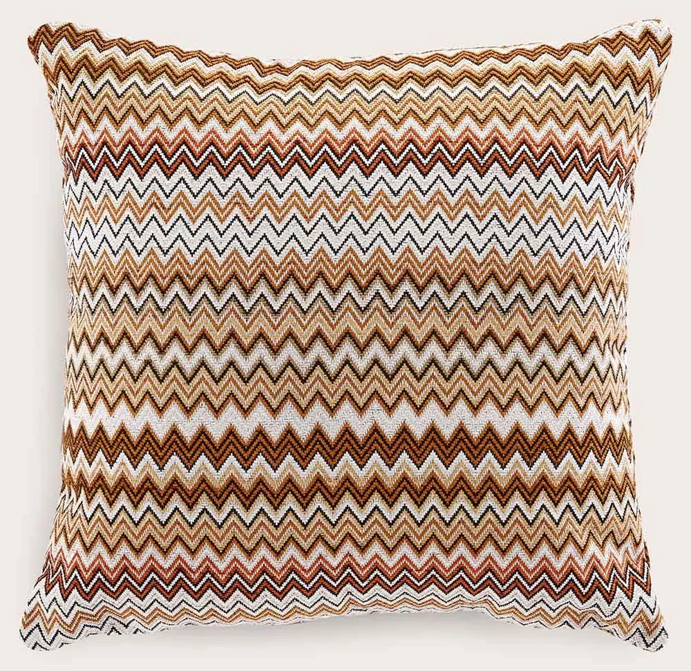 Coussin décoratif carré avec motif zigzag en cuivre, ocre, noir et blanc, sur tissu tissé.