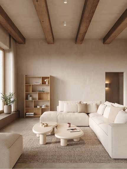 Salon beige avec canapé modulaire Duomo, tables basses rondes, bibliothèque en bois et grande fenêtre laissant entrer la lumière naturelle.