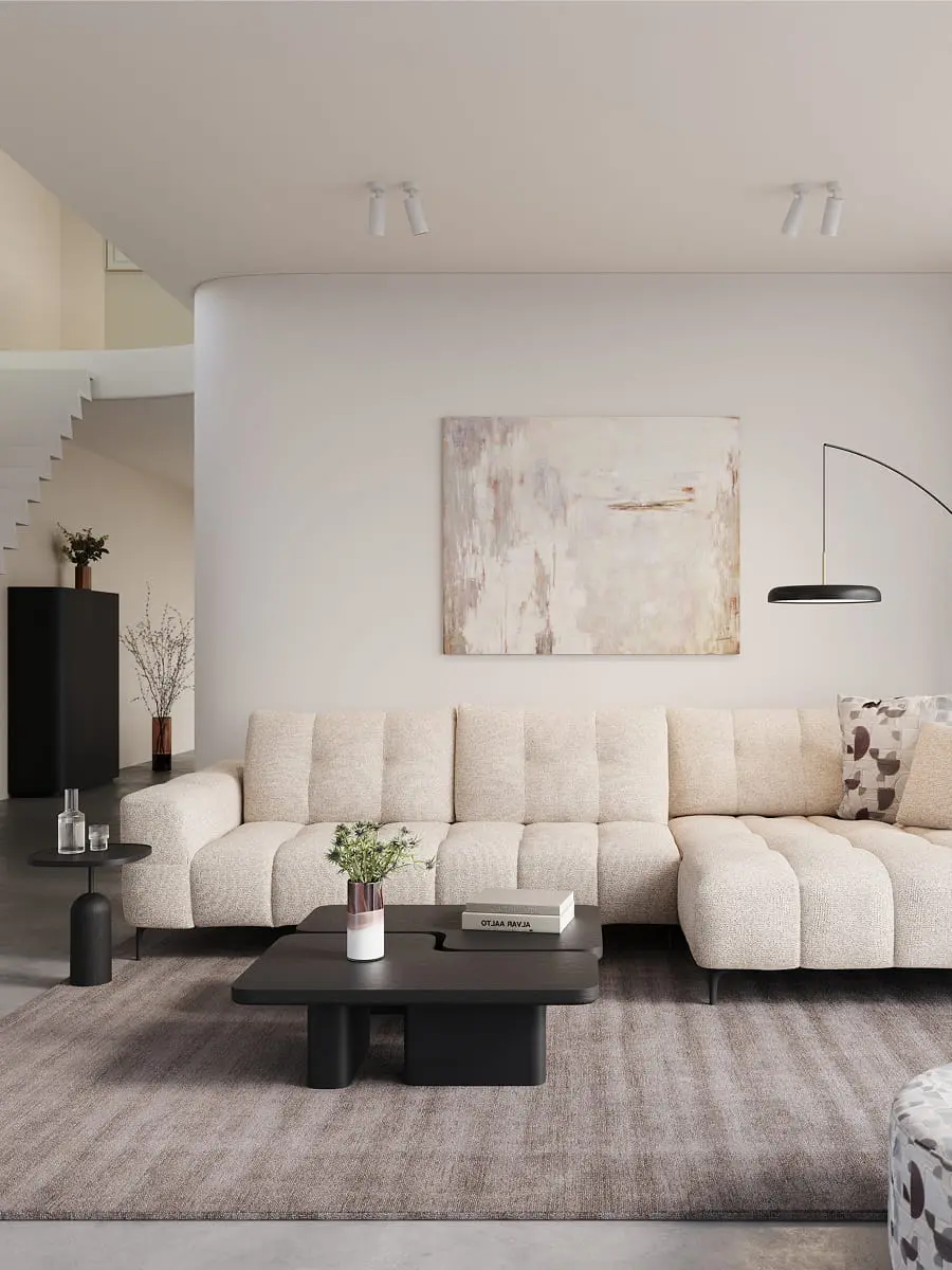 Canapé d’angle Campo beige avec assise profonde dans un salon moderne avec table basse noire, lampadaire et tons neutres.