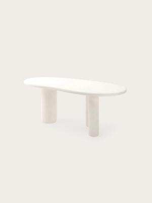 Witte organische eettafel met afgerond blad en drie cilindervormige poten.