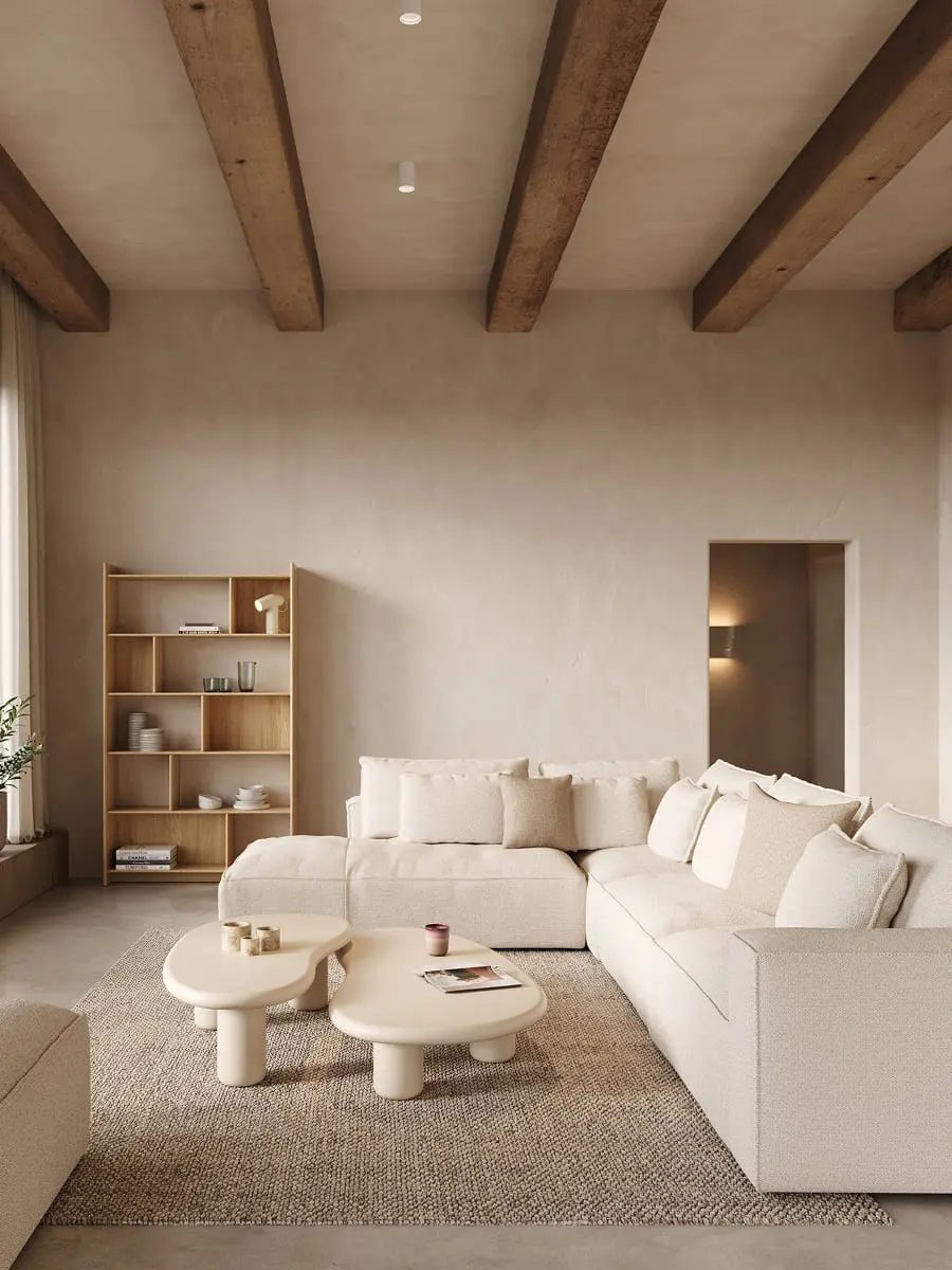 Beige hoeksofa in een rustige woonkamer met houten balken, open kast en organische salontafels op een neutraal tapijt.