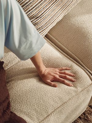 Une main reposant sur le tissu doux et texturé d'un canapé beige dans un espace de vie moderne.