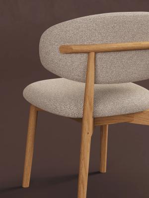 Detailbeeld van een eetkamerstoel met beige stoffen zitting, afgeronde rugleuning en een licht houten frame.