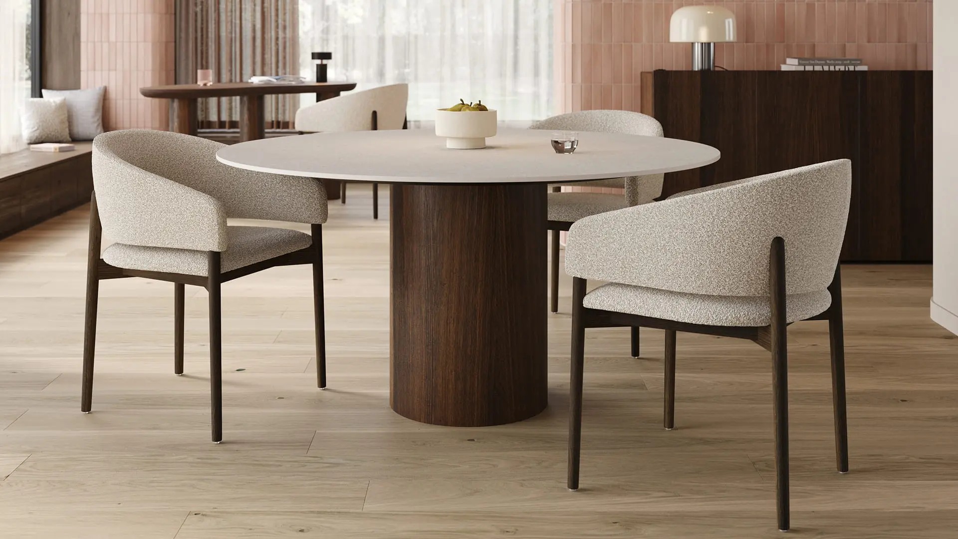 Table à manger ronde Amato au plateau clair et pied cylindrique en bois, entourée de chaises beige dans une salle à manger chaleureuse.