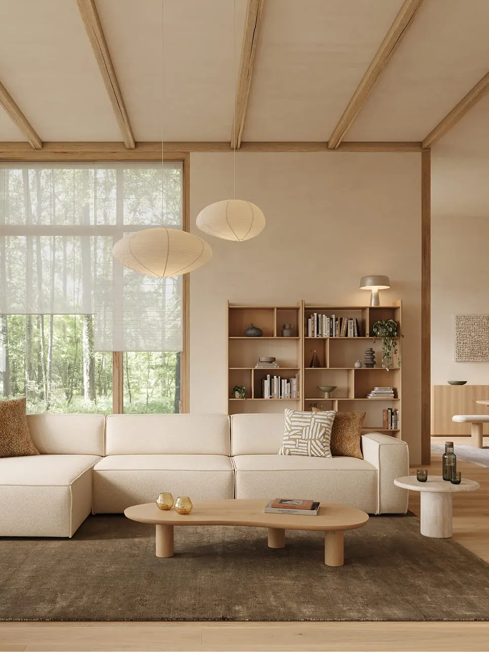 Table basse Artisano forme organique blob, finition claire, devant un canapé d’angle beige sur un tapis foncé.