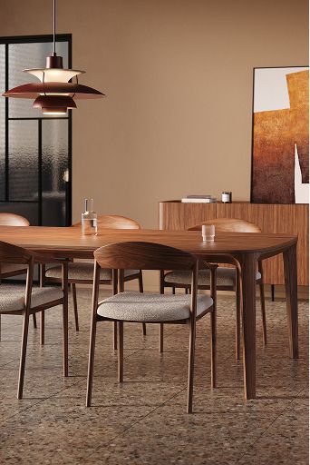 Warme eetkamer met houten eettafel en stoelen met gestoffeerde zittingen, onder een hanglamp; op de achtergrond een dressoir met kunstwerk en lamp.