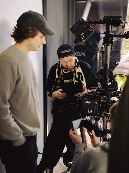 Coulisses sur le tournage : l’équipe prépare la prise autour d’une caméra professionnelle avec moniteur et stabilisateur.