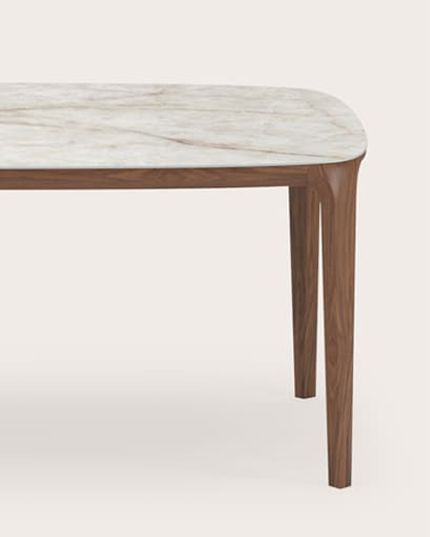Rechthoekige eettafel met licht natuurstenen blad en slanke poten in donker hout.