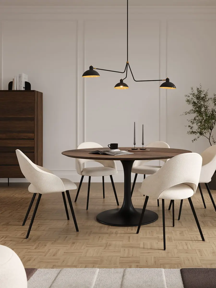 Coin repas avec table ronde en bois et quatre chaises Grado en tissu clair avec pieds noirs, sous une suspension noire.