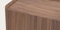 Detail van houten meubel met afgeronde hoek, fijn geribbelde zijkant en warm notenhout blad.