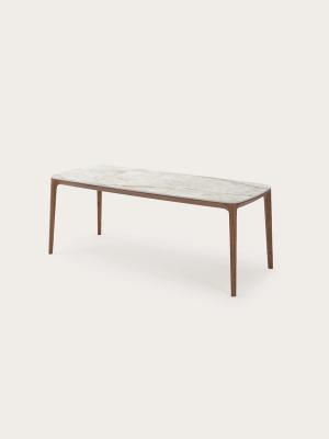 Rechthoekige eettafel met afgeronde hoeken, licht steenlook blad en slanke houten poten.