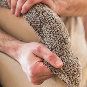 Gros plan sur des mains qui tendent le tissu d’habillage autour de l’assise de la chaise Cerso.