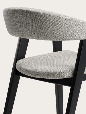 Détail du canapé Gubbio avec un revêtement en tissu gris clair, un dossier arrondi et des pieds en bois noir.