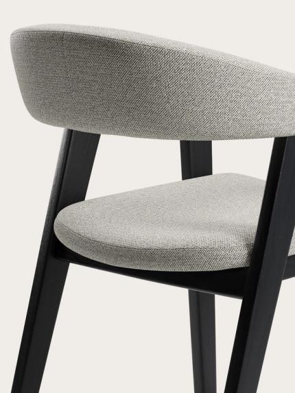 Détail du canapé Gubbio avec un revêtement en tissu gris clair, un dossier arrondi et des pieds en bois noir.