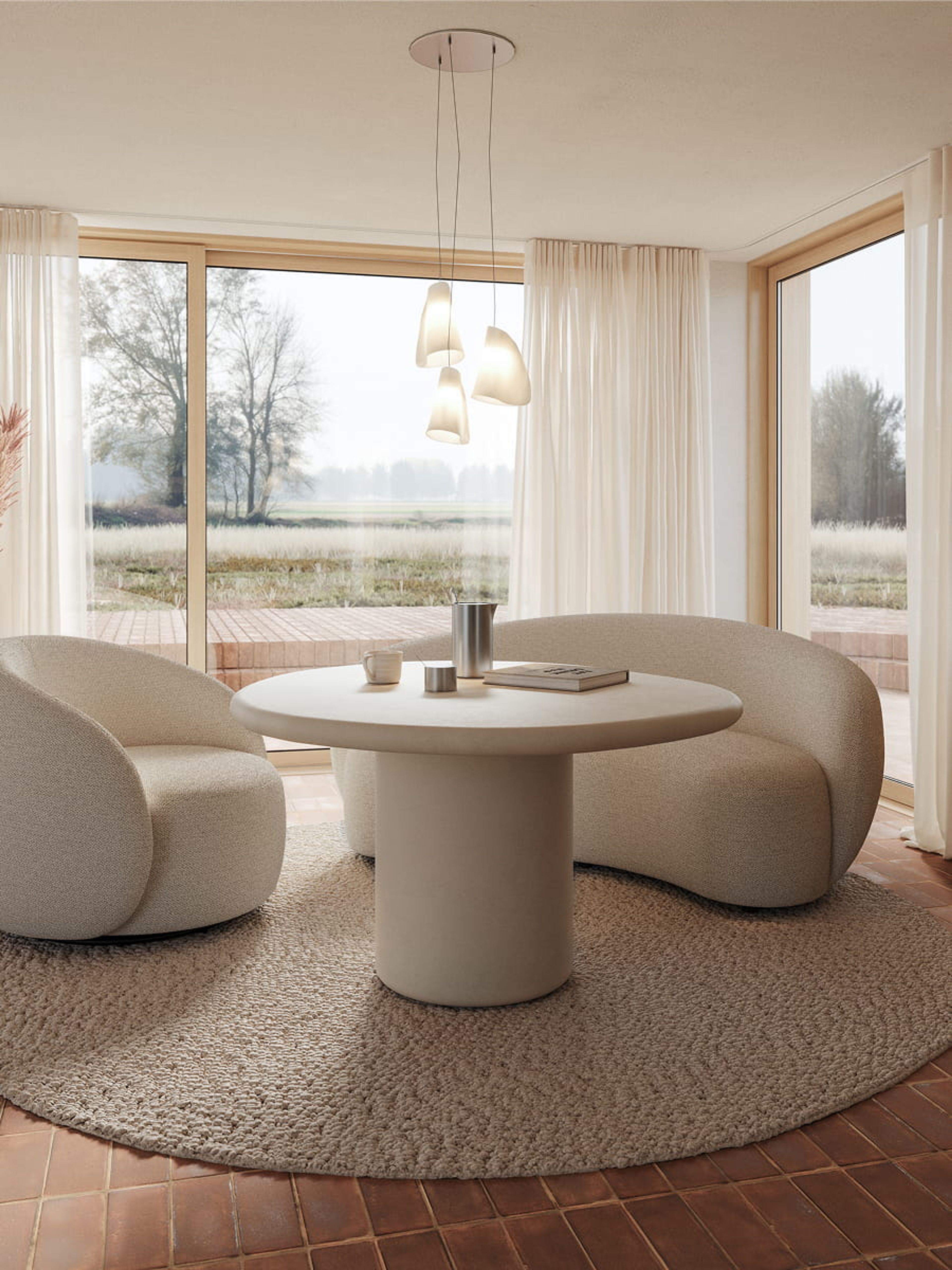Canapé Ponte beige aux formes arrondies autour d’une table à manger ronde dans un espace lumineux avec grandes fenêtres et vue sur la nature.
