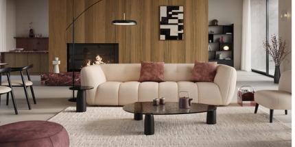 Moderne woonkamer met beige designzetel, donkere ronde salontafel, houten accentwand met haard en subtiele bordeaux details.