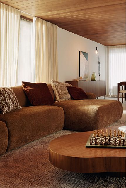 Sarpi zetel in roestbruine stof met ronde modules, in lichte woonkamer met houten plafond en eettafel.