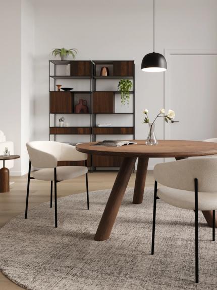 Lichte woonkamer met beige hoekzetel, ronde zwarte salontafels op een groot tapijt, wandkunst en open kast met planten.