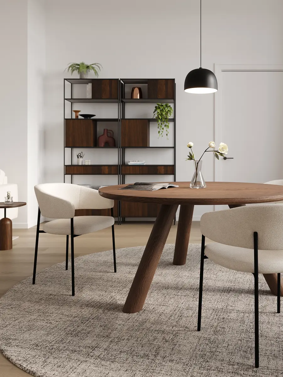 Salon lumineux avec canapé d’angle beige, tables basses rondes noires sur un grand tapis, tableau mural et étagère ouverte avec plantes.