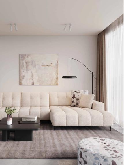 Beige hoekzetel Isola in lichte woonkamer met grote ramen, houten boekenkast, lage salontafel en zachte natuurlijke materialen.