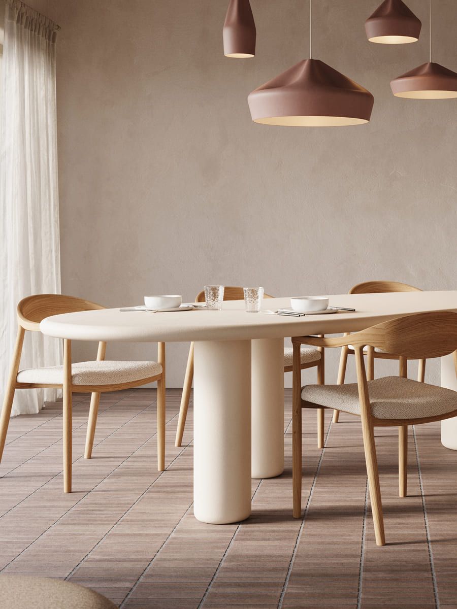 Rustige eetkamer met lange ovale tafel, houten stoelen en hanglampen, met balkenplafond, grote ramen en lichte houten kast.