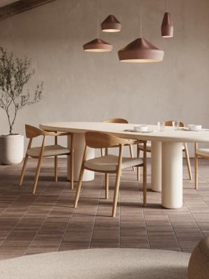 Moderne eetkamer met houten eetkamerstoelen, beige gestoffeerde zittingen en een ovale eettafel onder terracottakleurige hanglampen.