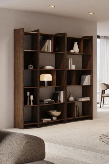 Donkerhouten open kast met boeken en decoratie in een licht interieur met eetruimte en fauteuils.