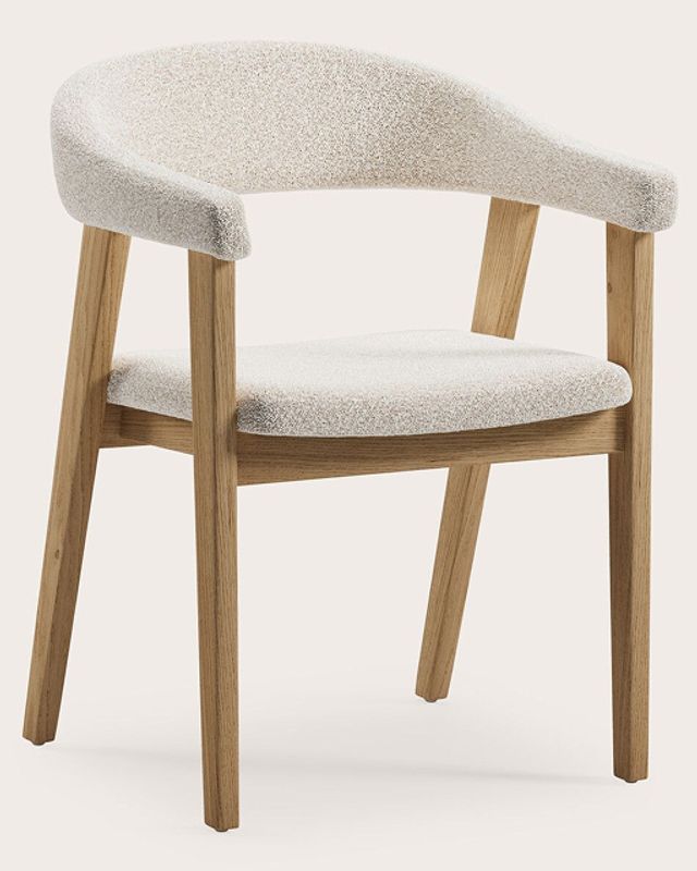 Houten stoel met armleuningen, lichte eiken poten en gestoffeerde zitting en rug in beige bouclé stof op neutrale achtergrond.