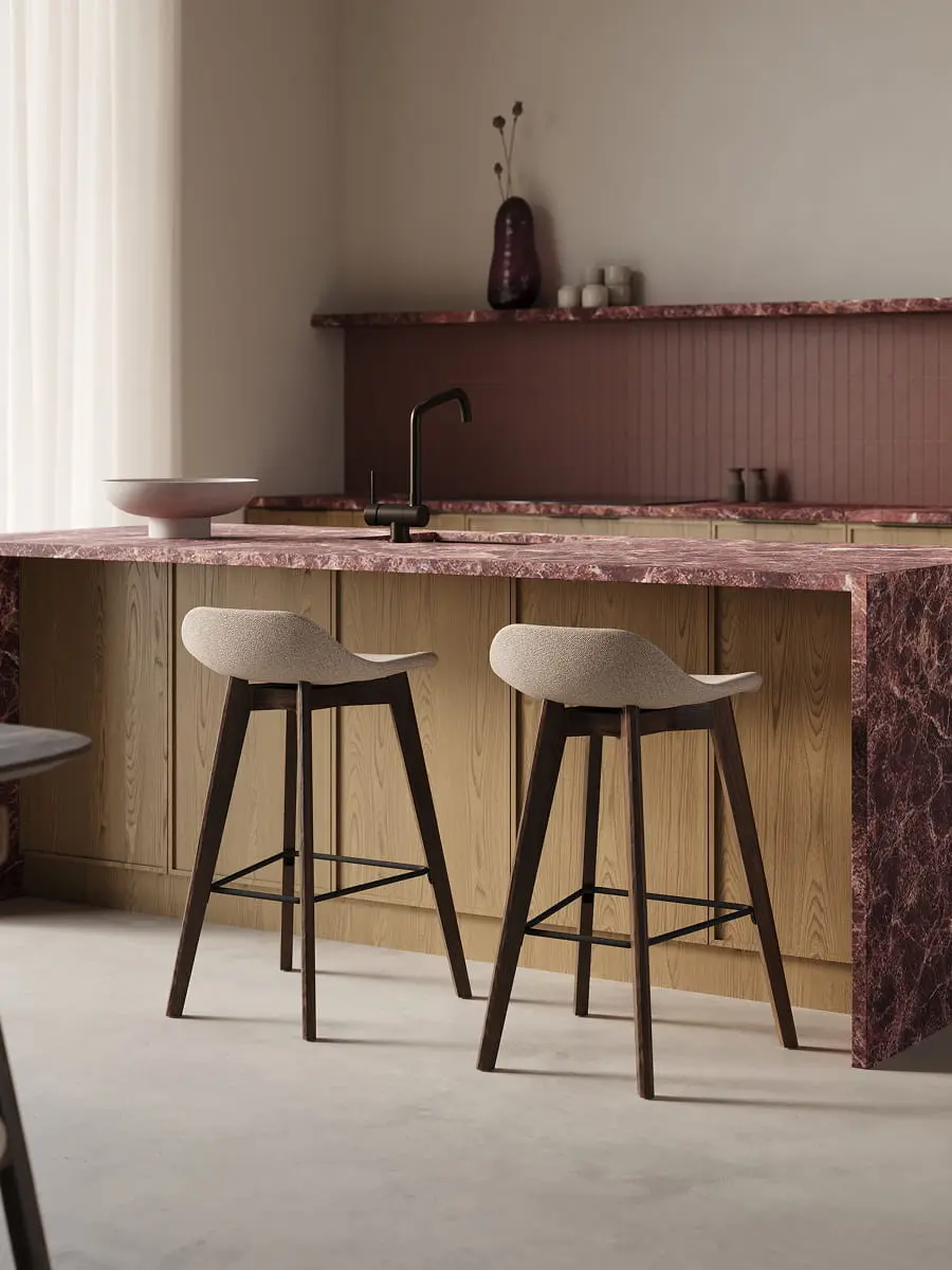 Deux tabourets de bar Vasco, assise claire et pieds foncés, devant un îlot en bois avec plan de travail en marbre rouge.