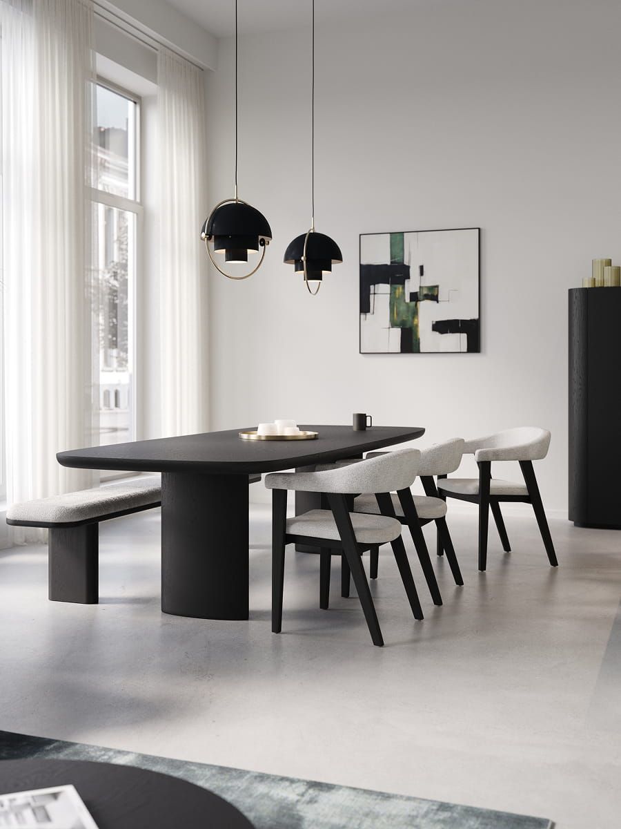 Eetkamer met zwarte tafel en Asiso stoelen met lichte bekleding, naast een bankje en grote ramen met zacht daglicht.