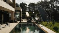 Plateau du spot TV Juntoo : maison moderne avec piscine, entourée d’éclairages et de réflecteurs pendant le tournage.